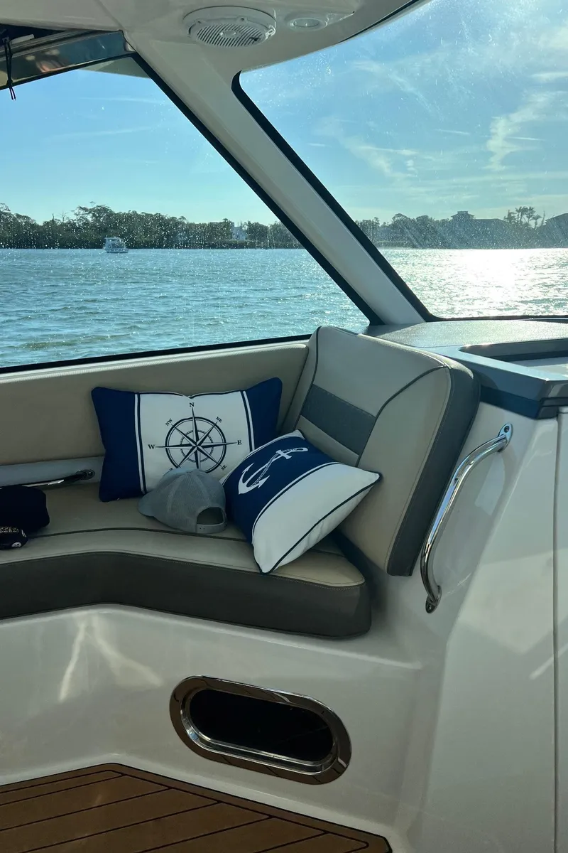 Slide: The Image of 2019 Pursuit 325 DC boat interior with nautical-themed cushions, overlooking serene water. - 13