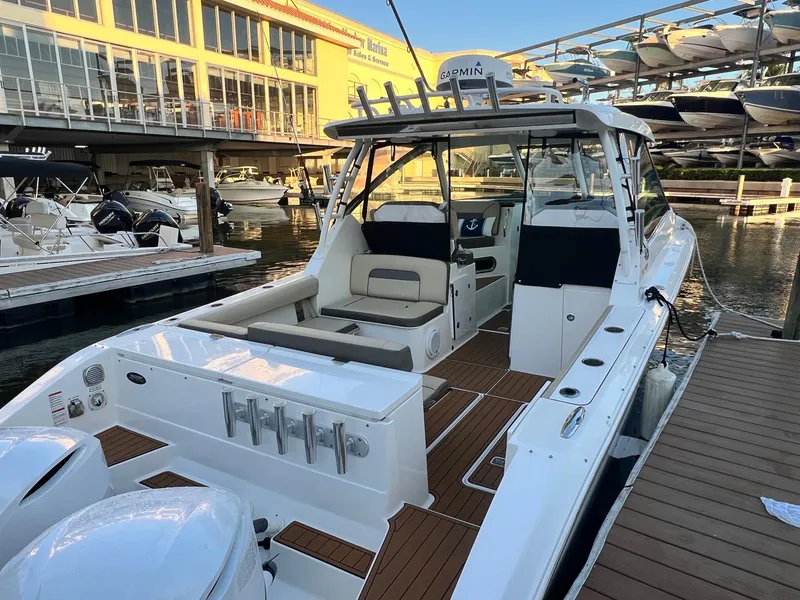 Slide: The Image of 2019 Pursuit 325 DC boat docked at marina, showcasing spacious deck and seating area. - 4