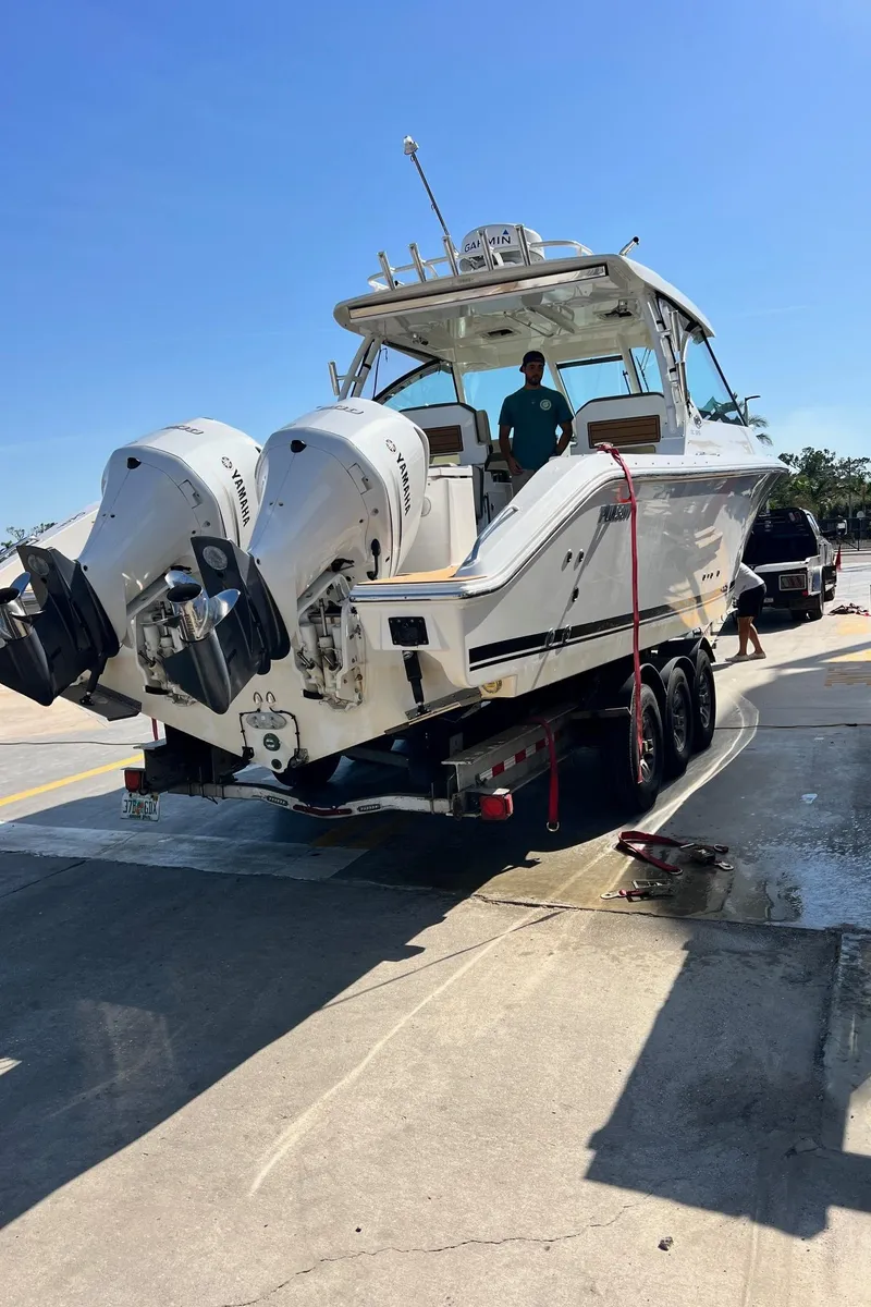 Slide: The Image of 2019 Pursuit 325 DC boat on trailer with dual Yamaha engines, parked outdoors. - 6