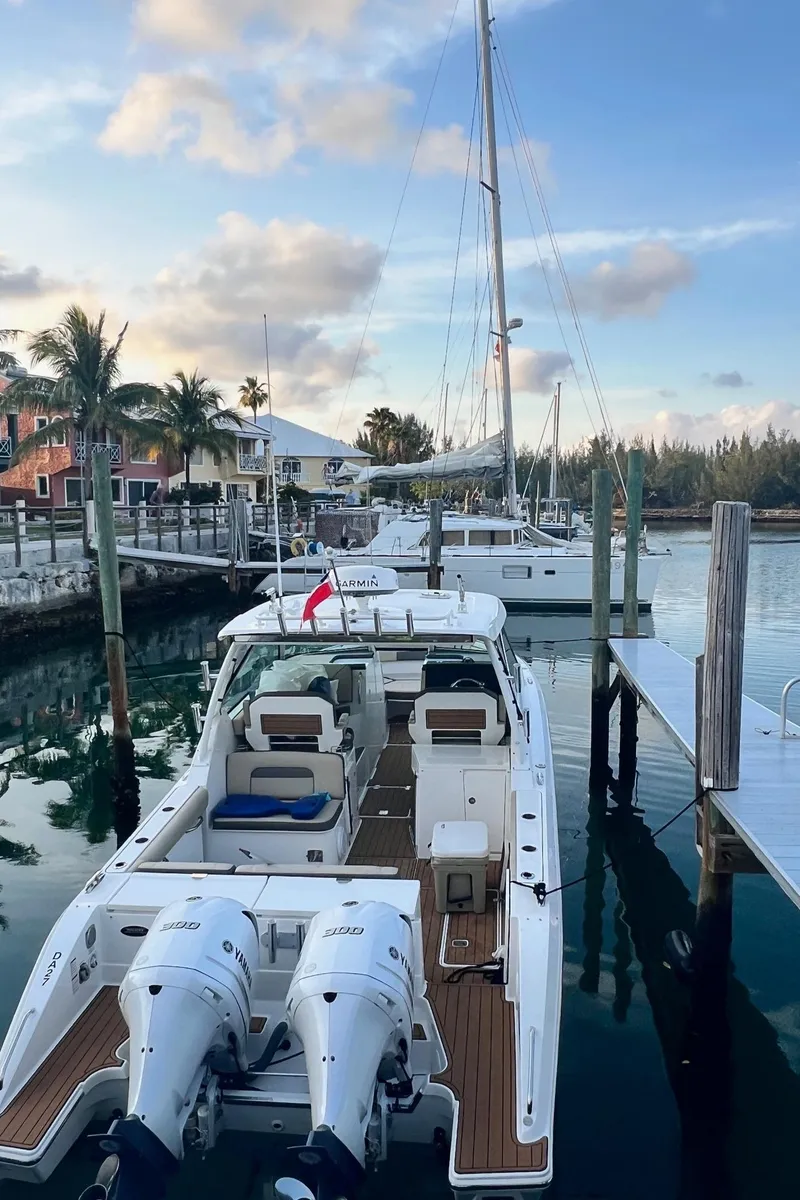 Slide: The Image of 2019 Pursuit 325 DC boat docked at marina with palm trees and clear sky. - 9