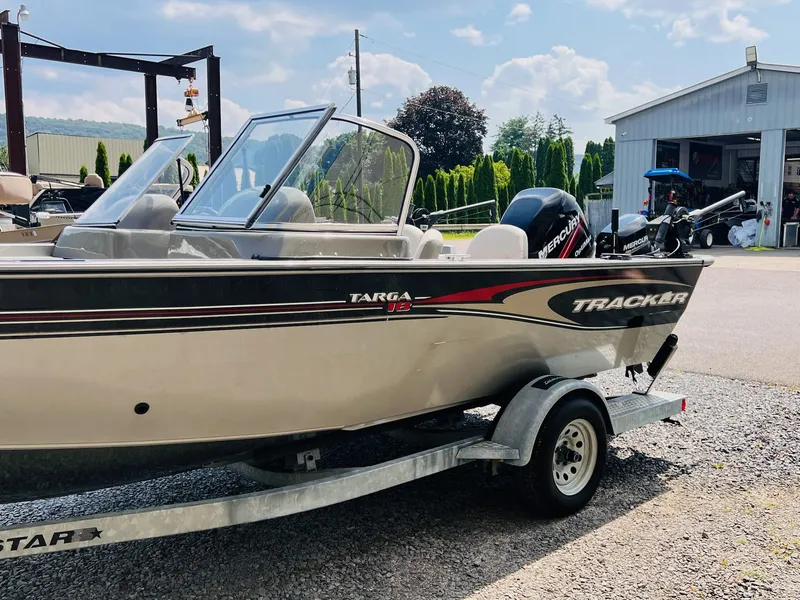 Slide: The Image of 2004 Tracker Targa WT boat on trailer, parked outside a garage under a sunny sky. - 34