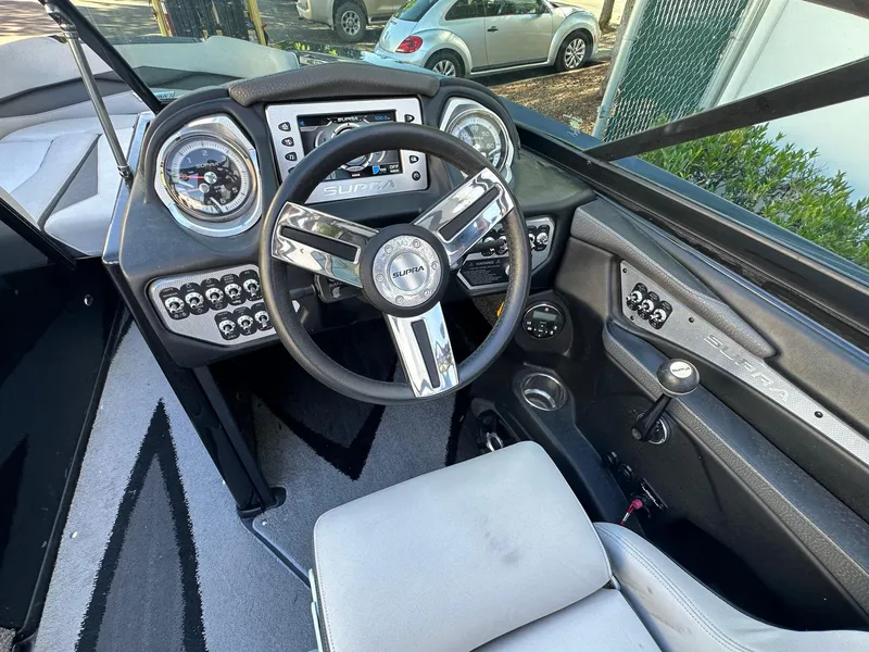 Slide: The Image of Interior of a 2013 Supra SA350 boat with steering wheel and dashboard controls. - 13