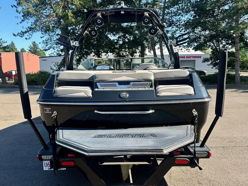 Slide: The Image of 2013 Supra SA350 boat, rear view, parked outdoors with trees in the background. - 8