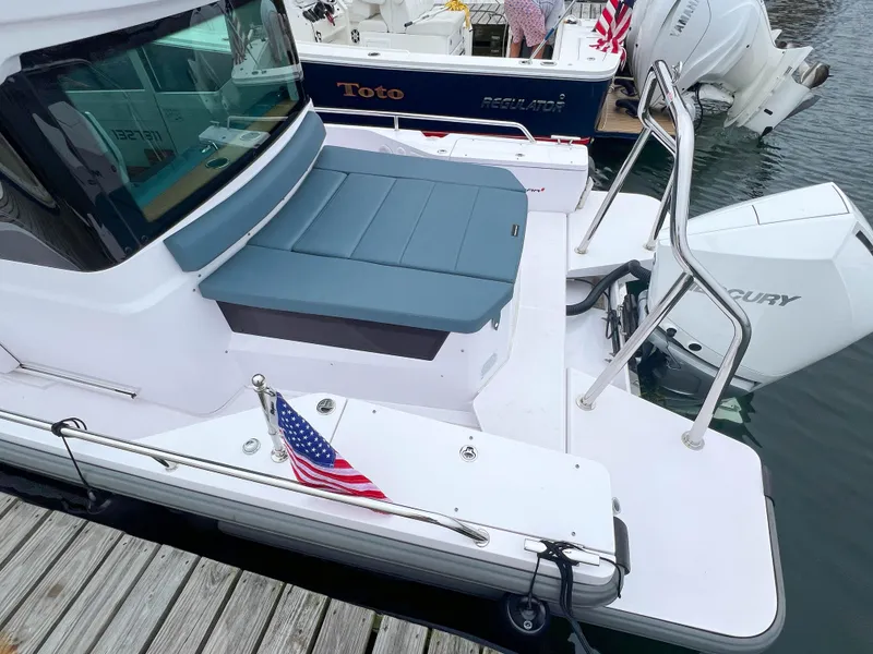 Slide: The Image of 2022 Axopar 28 Cabin Aft Cabin boat docked with American flag and Mercury engine. - 10