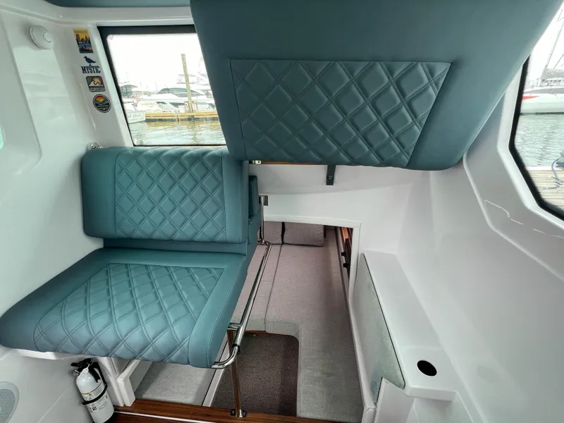 Slide: The Image of 2022 Axopar 28 Cabin Aft Cabin interior with quilted blue seating and window view. - 21