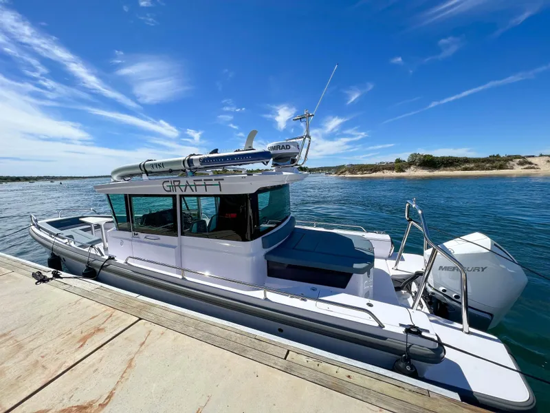 Slide: The Image of 2022 Axopar 28 Cabin Aft Cabin boat docked by the water under a clear blue sky. - 31