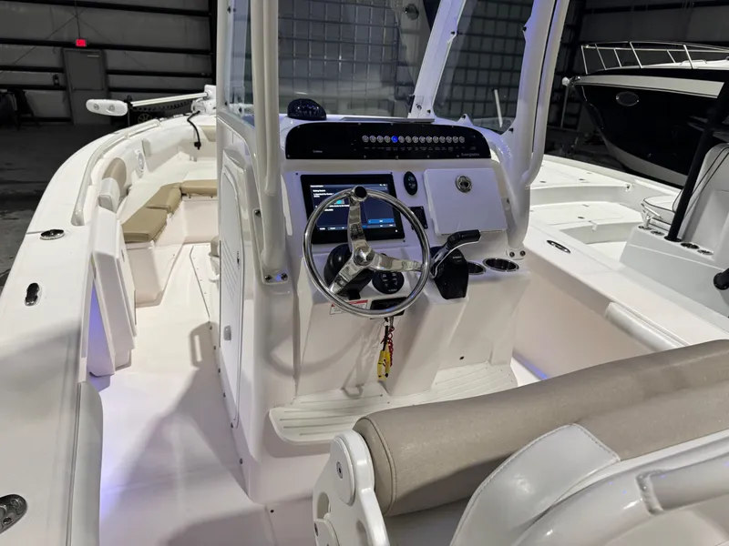 Slide: The Image of 2014 Everglades 243 CC boat interior with steering console and seating in a warehouse. - 19