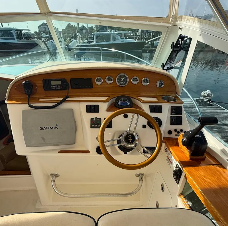 Slide: The Image of 2009 Hunt Yachts Harrier 29 helm with Garmin navigation, wooden accents, and marina view. - 22