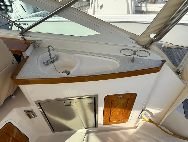Slide: The Image of 2009 Hunt Yachts Harrier 29 interior with sink and storage, featuring wood accents and stainless steel fixtures. - 16
