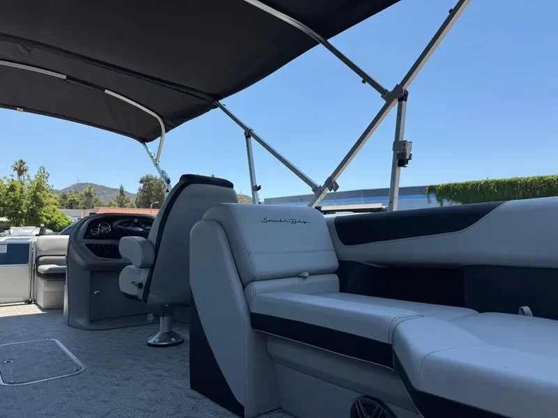 Slide: The Image of 2025 South Bay 222 LE pontoon boat interior with seating and canopy under clear sky. - 15