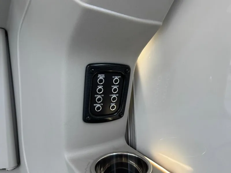 Slide: The Image of Control panel on 2025 South Bay 222 LE boat, featuring various switches and cup holder. - 19