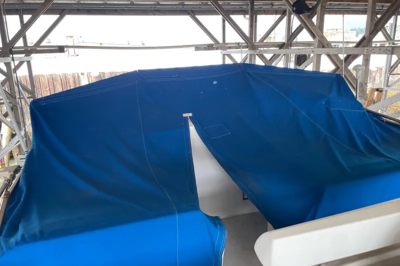 Slide: The Image of Blue tarp covering a 1964 Grand Banks 42 Classic boat in a wooden structure. - 10