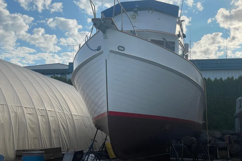 Slide: The Image of 1964 Grand Banks 42 Classic boat on dry dock under a partly cloudy sky. - 4