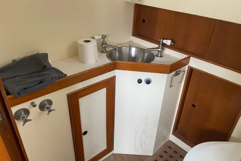 Slide: The Image of 1964 Grand Banks 42 Classic boat bathroom with sink, wooden cabinets, and towel. - 57