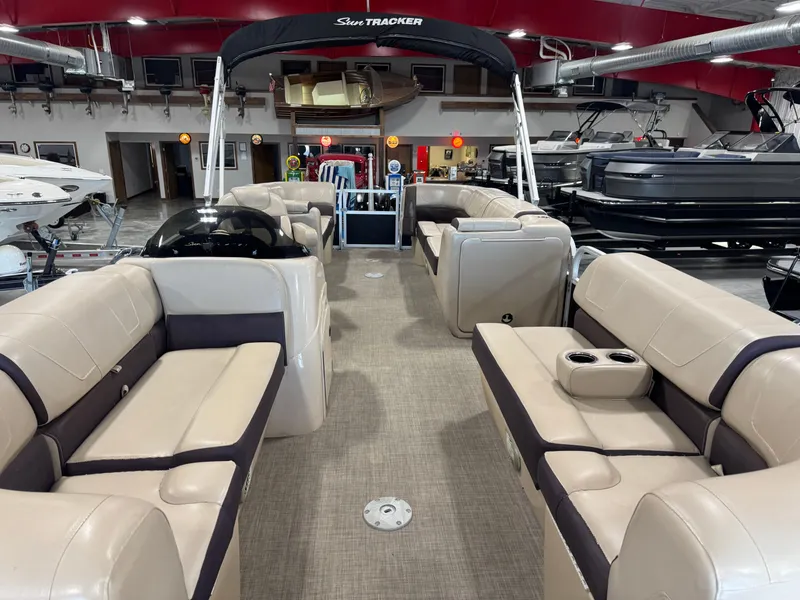 Slide: The Image of 2018 Sun Tracker Party Barge 22 DLX interior with beige seating in a showroom. - 7