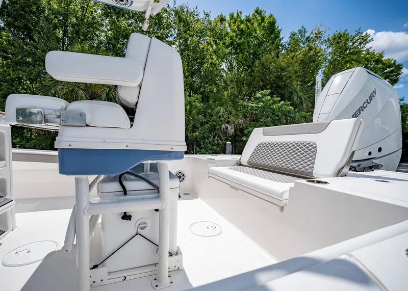 Slide: The Image of 2024 Caymas 26 HB boat interior with seating and Mercury engine, surrounded by lush greenery. - 10