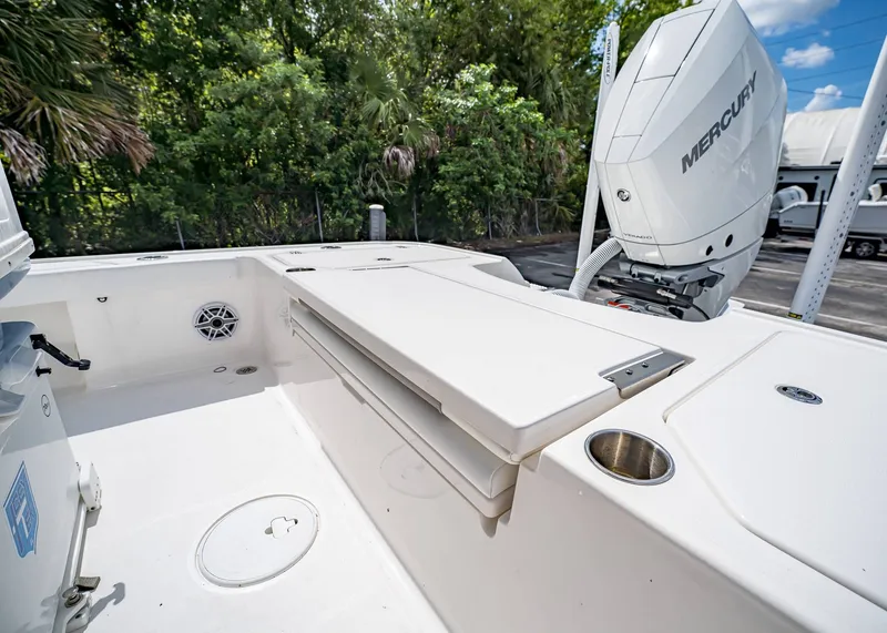 Slide: The Image of 2024 Caymas 26 HB boat deck with Mercury engine, featuring storage and cup holder. - 11