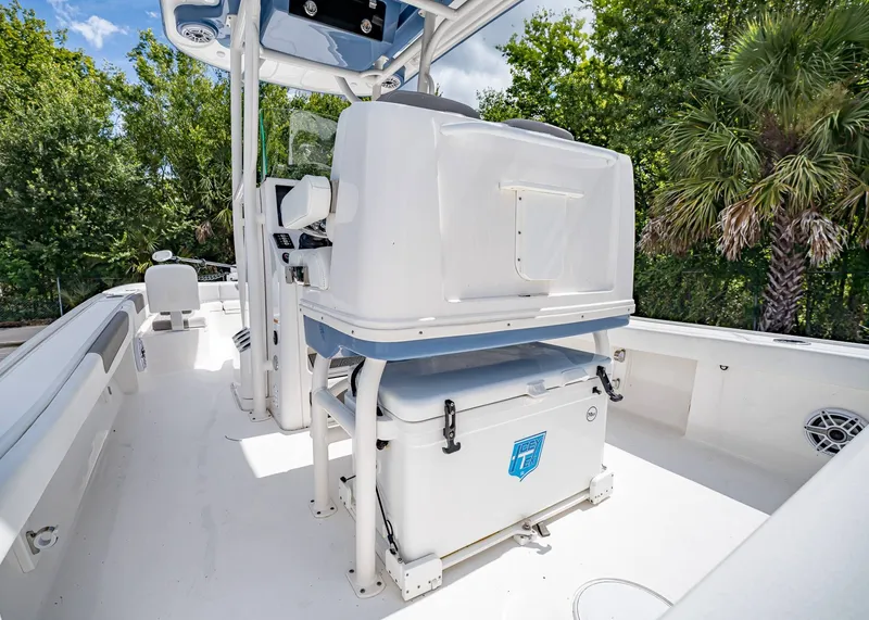 Slide: The Image of 2024 Caymas 26 HB boat interior with seating and storage, surrounded by lush greenery. - 12