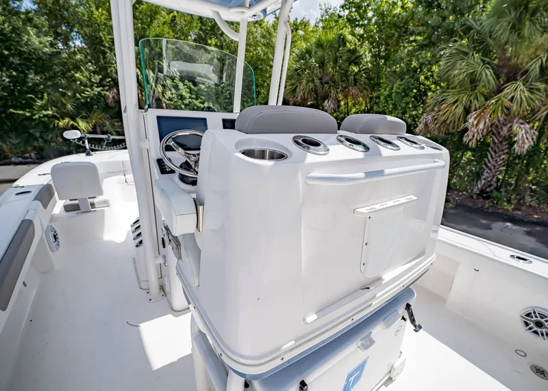 Slide: The Image of 2024 Caymas 26 HB boat interior with helm station and seating, surrounded by lush greenery. - 14