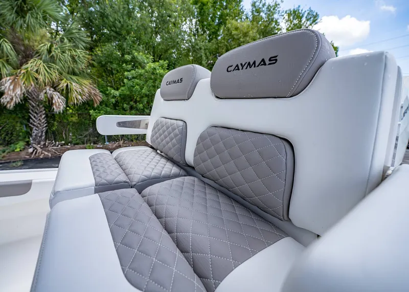 Slide: The Image of 2024 Caymas 26 HB boat seats with quilted gray upholstery, surrounded by lush greenery. - 21