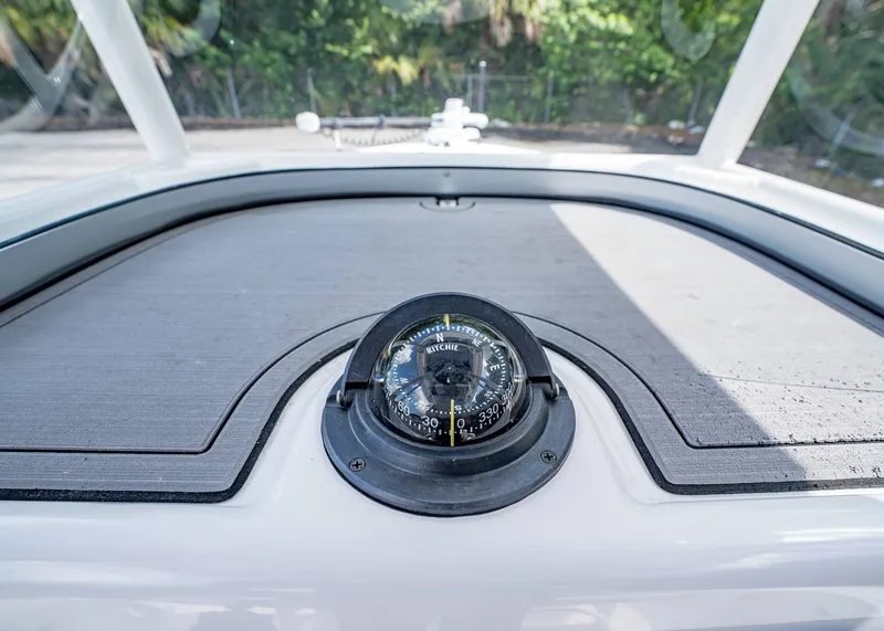 Slide: The Image of Compass on 2024 Caymas 26 HB boat dashboard, surrounded by lush greenery. - 24