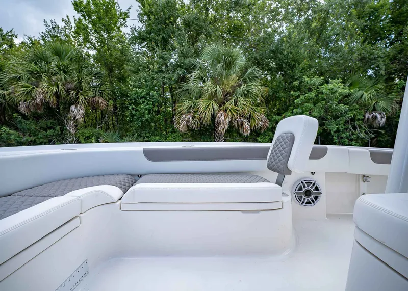 Slide: The Image of 2024 Caymas 26 HB boat interior with cushioned seating and lush greenery background. - 34