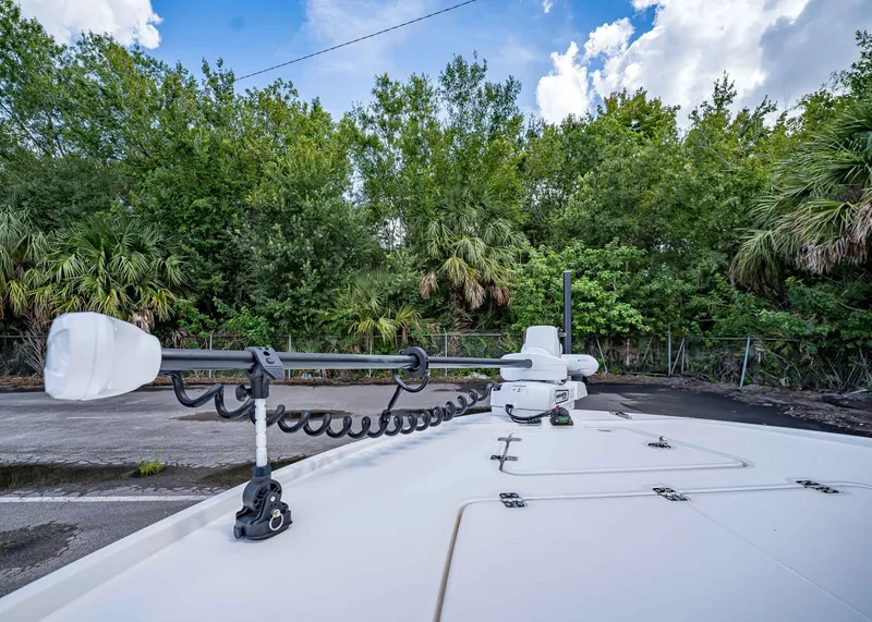 Slide: The Image of 2024 Caymas 26 HB boat with trolling motor, surrounded by lush greenery and blue sky. - 38