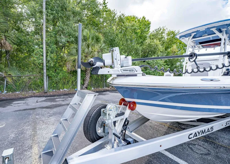 Slide: The Image of 2024 Caymas 26 HB boat on trailer with Minn Kota motor, parked outdoors. - 6