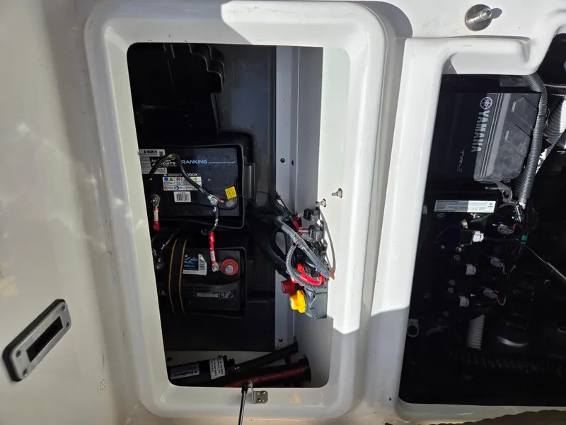 Slide: The Image of 2022 Yamaha Boats 210 FSH Deluxe battery compartment with wiring and components. - 21
