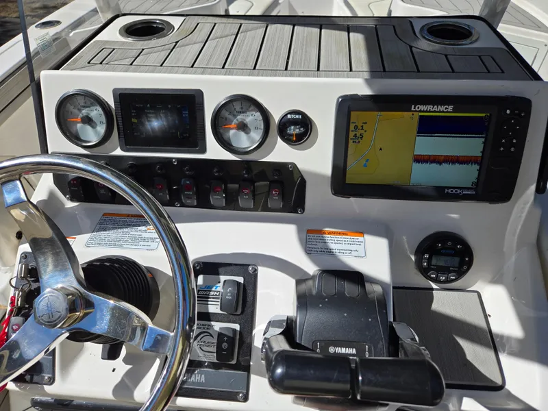 Slide: The Image of 2022 Yamaha Boats 210 FSH Deluxe dashboard with steering wheel and navigation display. - 25