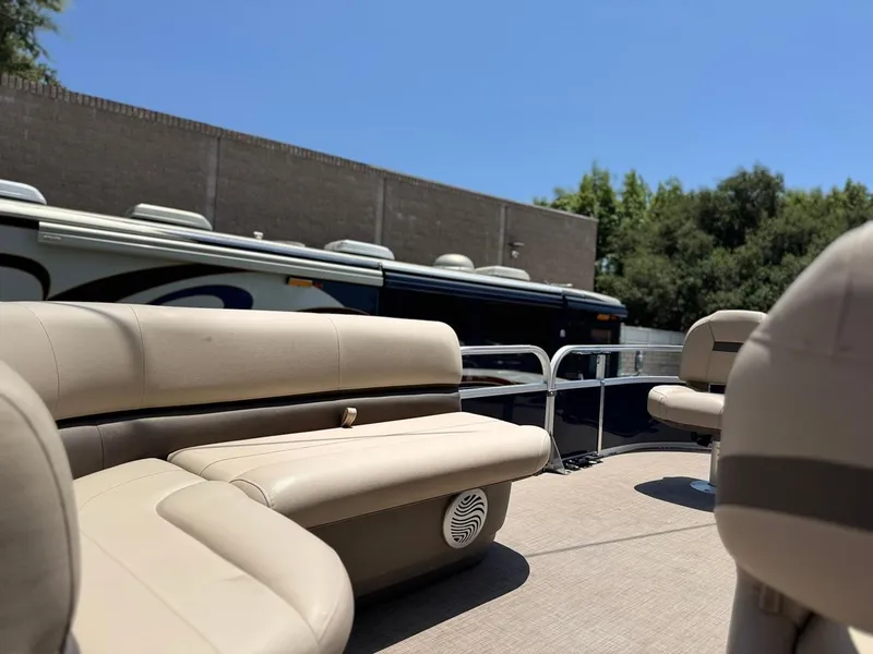 Slide: The Image of 2023 Sun Tracker Bass Buggy 16 XL Select pontoon boat with beige seating, parked outdoors. - 11