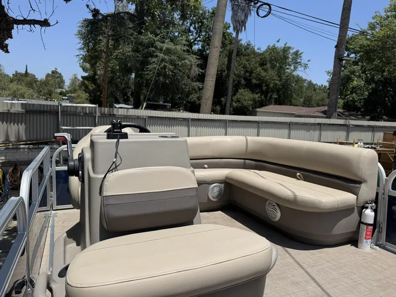 Slide: The Image of 2023 Sun Tracker Bass Buggy 16 XL Select pontoon boat with beige seating and outdoor setting. - 6