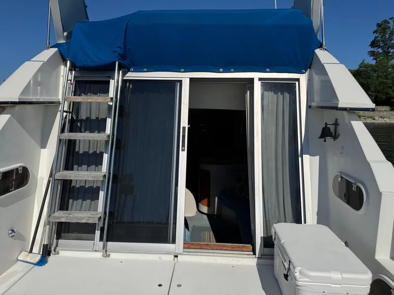 Slide: The Image of 1990 Carver 30 Santego boat with blue canopy and sliding glass doors. - 4