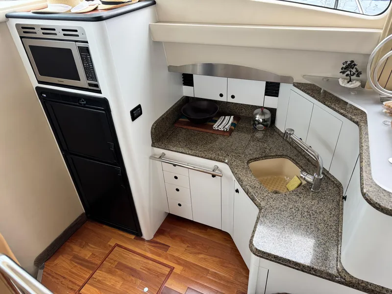 Slide: The Image of 2005 Sea Ray 420 Sedan Bridge kitchen with granite countertops, microwave, and sink. - 11