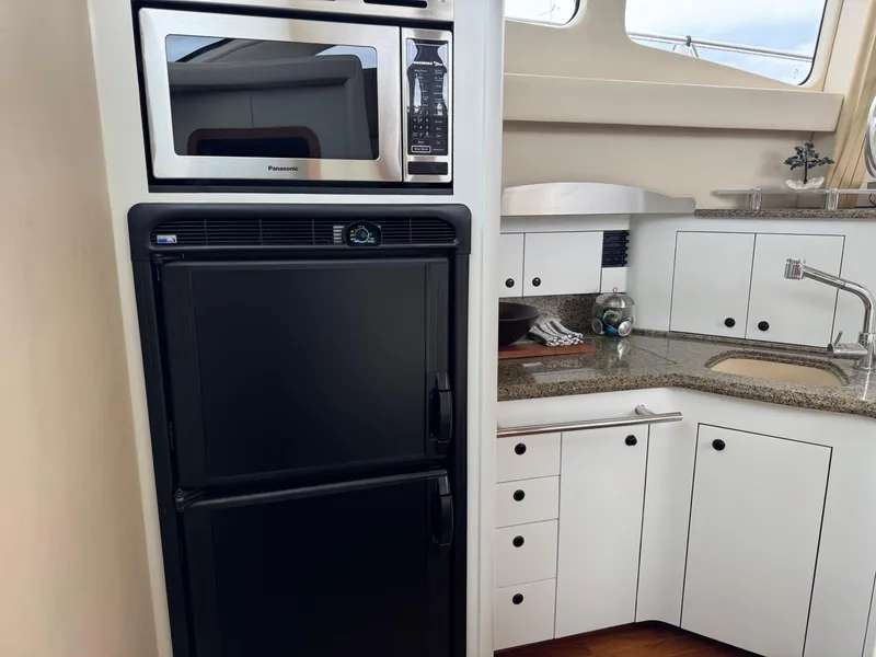 Slide: The Image of 2005 Sea Ray 420 Sedan Bridge kitchen with microwave, fridge, and granite countertop. - 22
