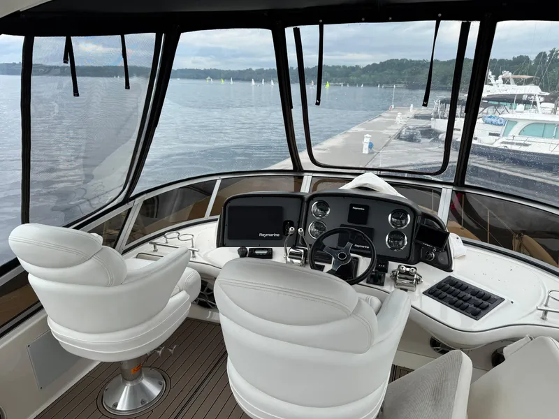 Slide: The Image of 2005 Sea Ray 420 Sedan Bridge helm with white seats, overlooking marina and water. - 27
