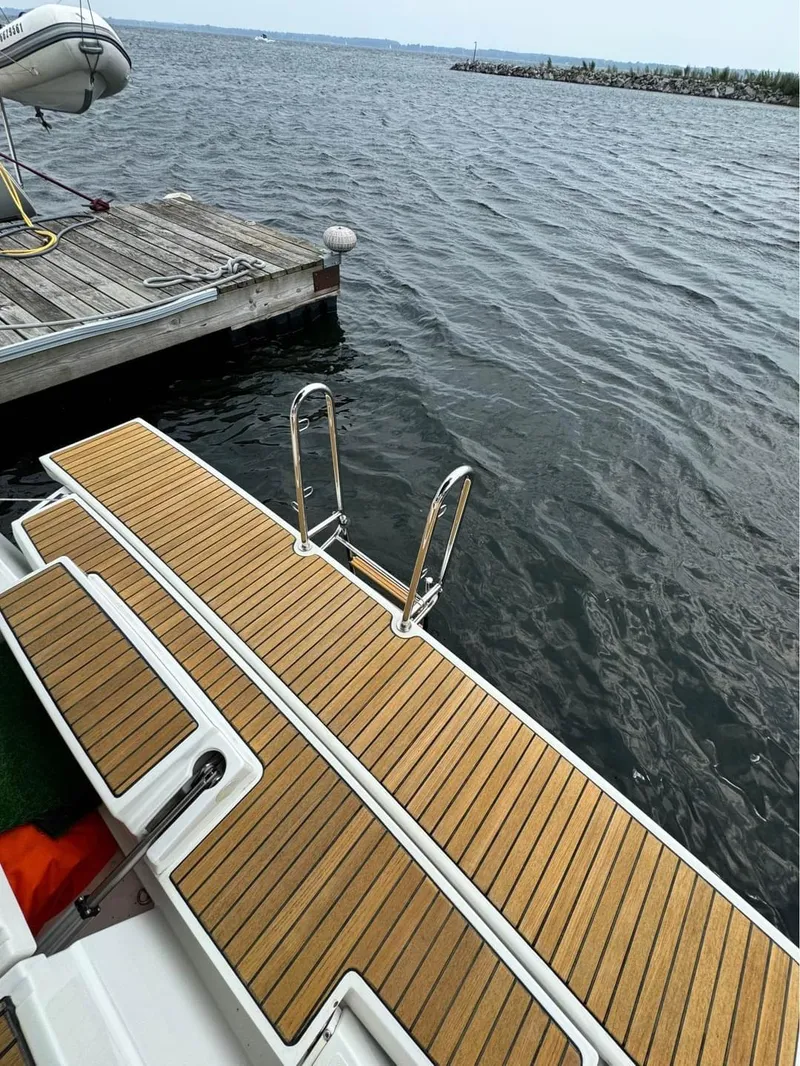 Slide: The Image of Beneteau Oceanis 48 (2013) swim platform with ladder, docked by a wooden pier. - 9