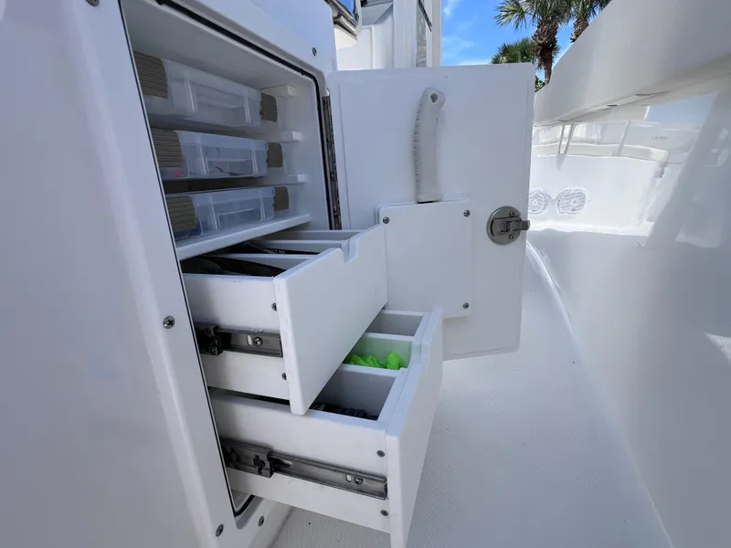 Slide: The Image of 2024 Sea Hunt Ultra 239 SE boat storage compartments with open drawers and tackle boxes. - 38