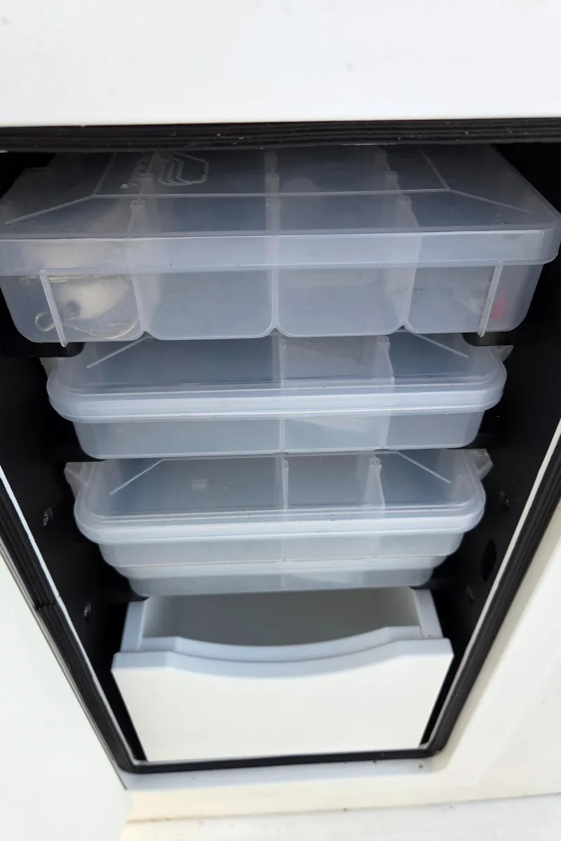 Slide: The Image of Storage compartments on a 2021 Regulator 31 CC boat, featuring organized plastic containers. - 14