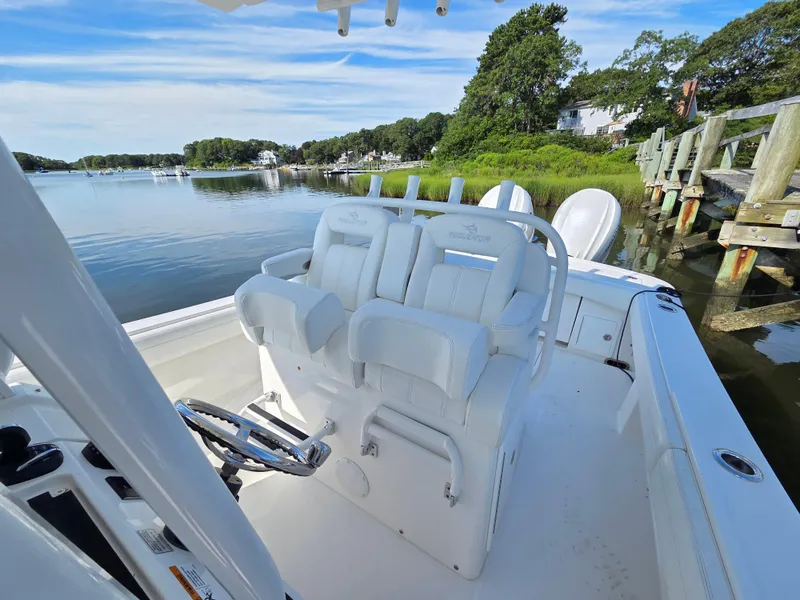 Slide: The Image of 2021 Regulator 31 CC boat interior with white seating, docked by a scenic waterfront. - 17