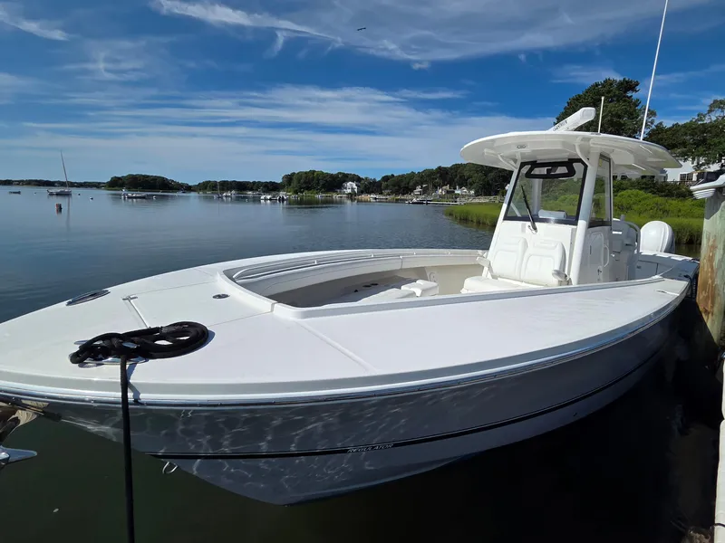 Slide: The Image of 2021 Regulator 31 CC boat docked on a calm lake under a clear blue sky. - 2