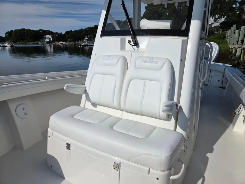 Slide: The Image of 2021 Regulator 31 CC boat with white seating, docked by a serene waterfront. - 20