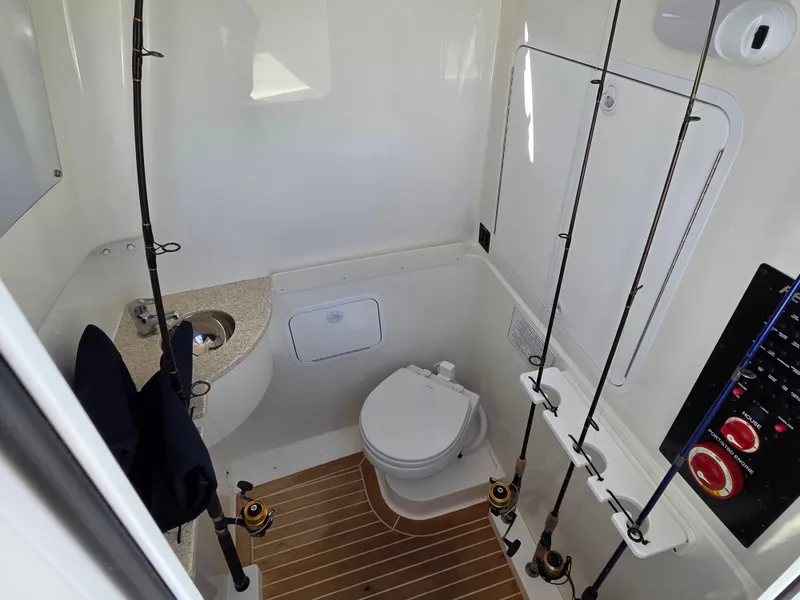 Slide: The Image of 2021 Regulator 31 CC boat interior with toilet, fishing rods, and control panel. - 22
