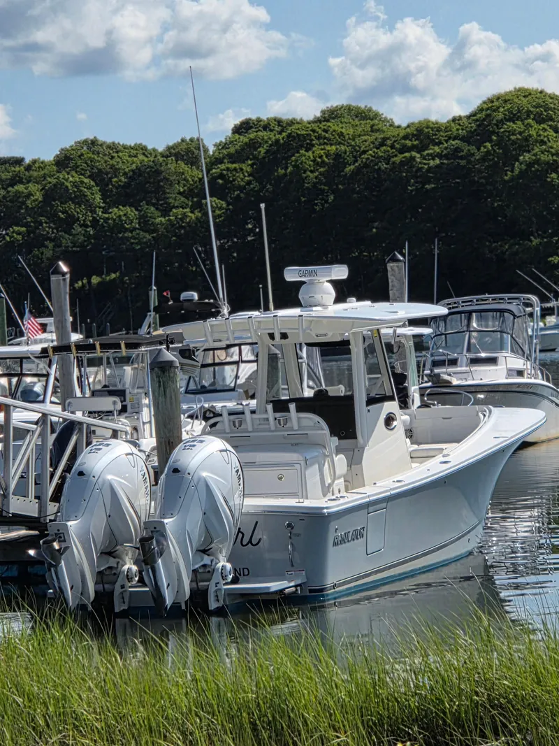 Slide: The Image of 2021 Regulator 31 CC boat docked, featuring dual outboard engines, surrounded by lush greenery. - 3