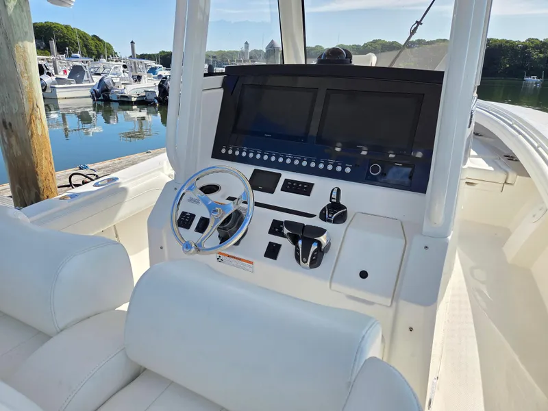 Slide: The Image of 2021 Regulator 31 CC boat console with dual screens and steering wheel at marina. - 8