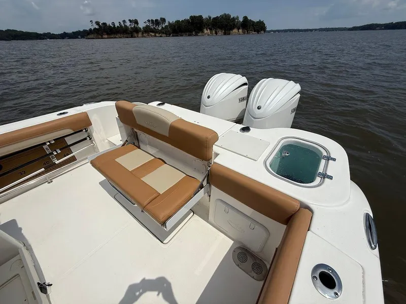 Slide: The Image of 2023 NauticStar 28 XS boat with tan seating and dual Yamaha engines on a lake. - 10