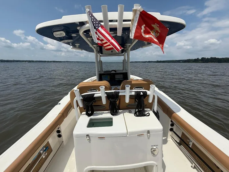 Slide: The Image of 2023 NauticStar 28 XS boat on water, featuring flags and fishing rod holders. - 14