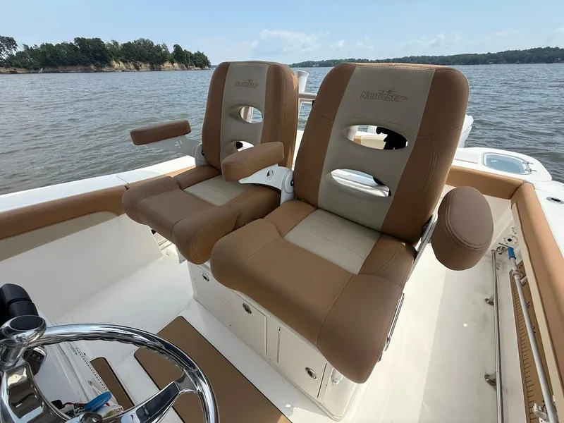 Slide: The Image of 2023 NauticStar 28 XS boat interior with tan and cream seating on a calm lake. - 18
