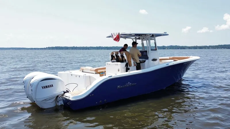 Slide: The Image of 2023 NauticStar 28 XS boat on water with Yamaha engines, two people onboard. - 4