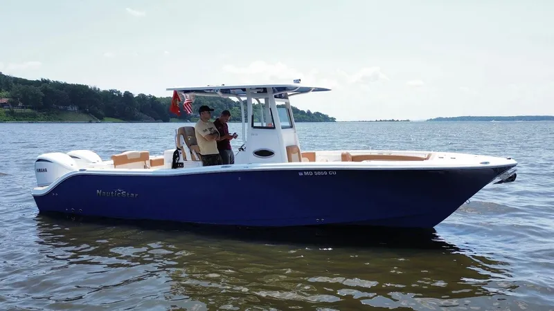 Slide: The Image of 2023 NauticStar 28 XS boat on water with two people onboard, scenic background. - 5